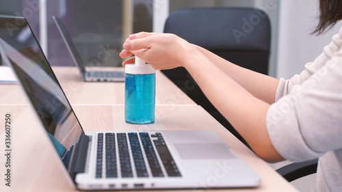 Young asian woman working with computer laptop and using hand sanitizer gel for prevent the pandemic of Covid-19 and Coronavirus, work from home and self quarantine concept