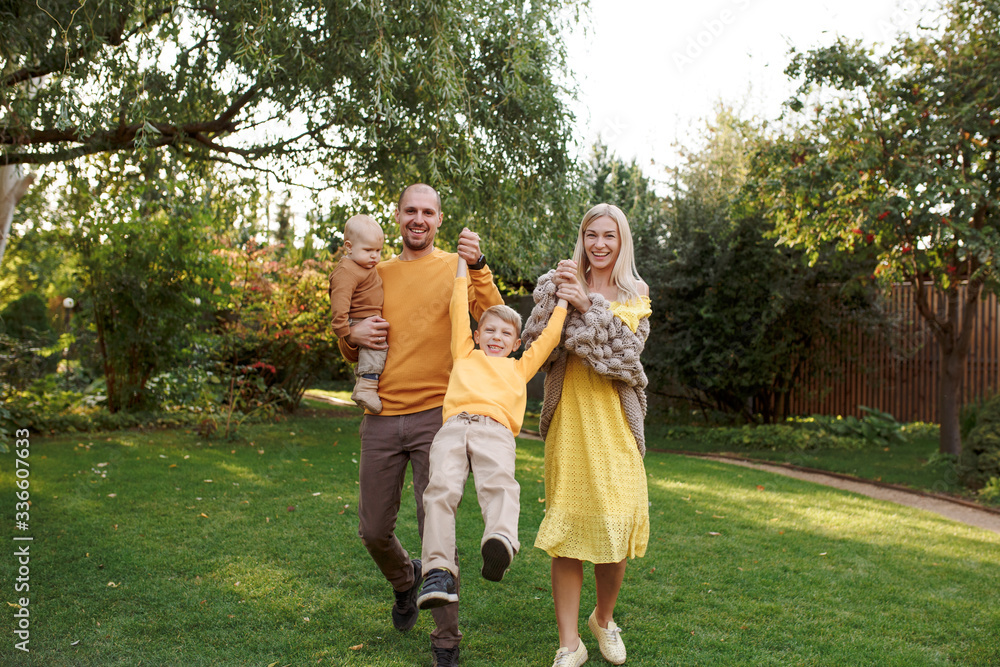 Obraz premium family in nature, summer or autumn, green grass trees in green leaves, a pond in nature, mom blonde in a yellow dress, dad, husband, older son and youngest son, two children, a large and happy family