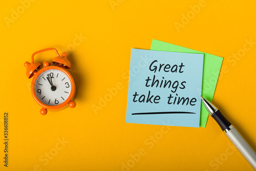 Fototapeta Great things take time - written in note on desk with little clock