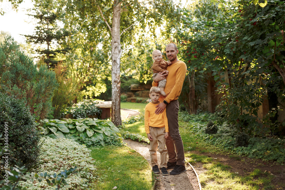 family in nature, summer or autumn, green grass trees in green leaves, a pond in nature, mom blonde in a yellow dress, dad, husband, older son and youngest son, two children, a large and happy family