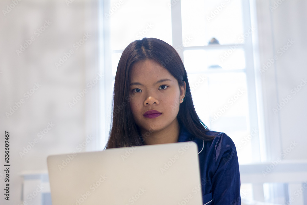 Young asian smiling woman working on laptop in her bedroom. Happy morning Young asian smiling woman working on laptop in her bedroom. Happy morning