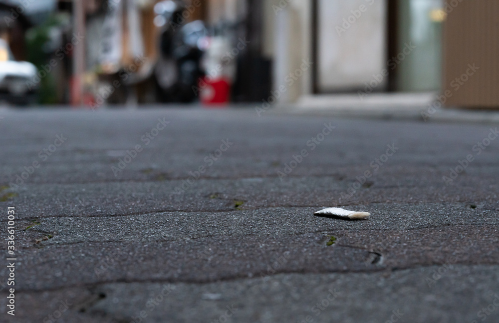 A cigarette butt that is abandoned and crushed on the roadside