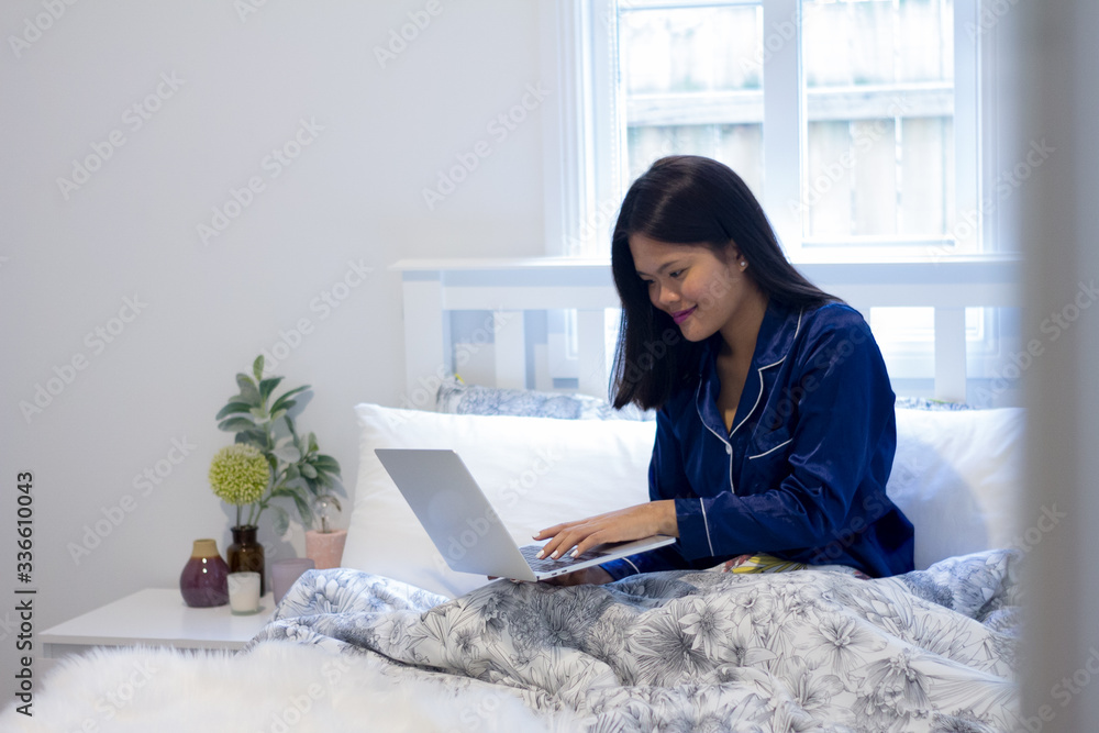 Young asian smiling woman working on laptop in her bedroom. Happy morning Young asian smiling woman working on laptop in her bedroom. Happy morning