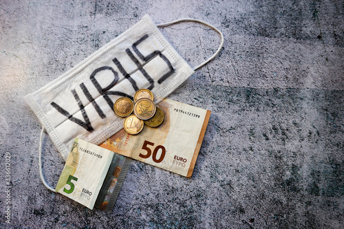 World financial crisis wallpaper new covid 2019 coronavirus strikes europe economy medical mask on a stone background with the inscription virus with five and fifty euro banknote and coins