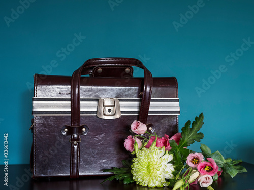 closeup of white Chrysant flower and pink flowers in front of a doctors case, with shadows, against green wall photo