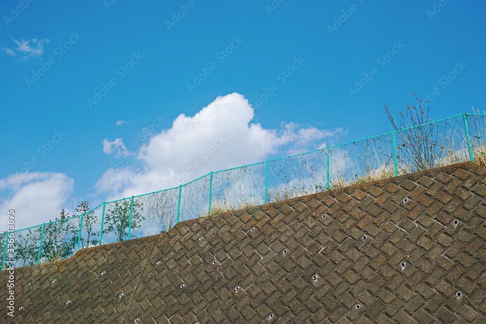 擁壁とフェンスと白い雲のある青空