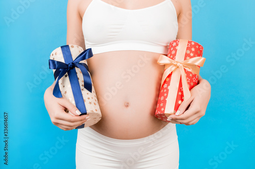 Wallpaper Mural Close up of pregnant woman in white underwear holding two gift boxes at blue background. Is it a boy or a girl? Childbirth preparation. Copy space Torontodigital.ca