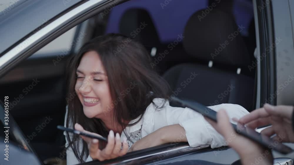 Emotional girl in car speaking with someone with tablet and smiling Emotional girl in car speaking with someone with tablet and smiling