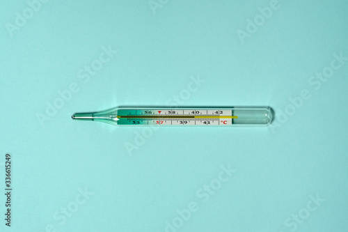 Medical thermometer shows high body temperature 39.9 - 40 celsius. Mercury thermometer flat lay on a blue background.