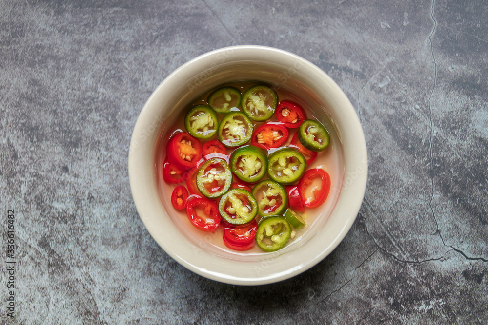 Green and red pickled chili in vinegar on grey background. Top view Green and red pickled chili in vinegar on grey background. Top view