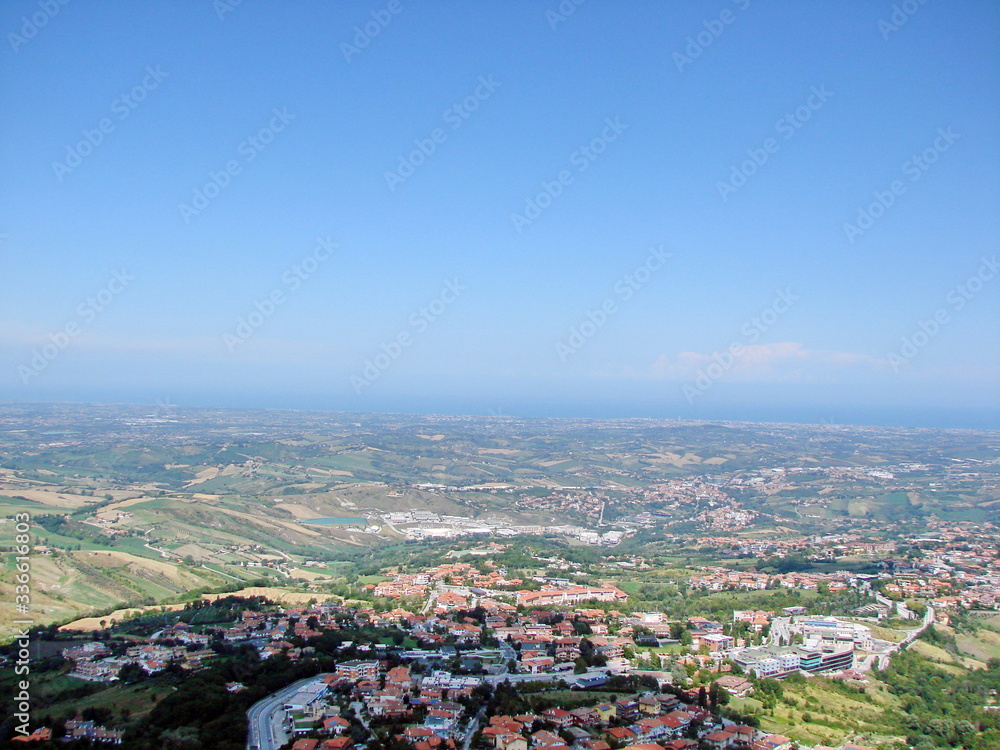 Panoramic view of mountain ranges on the horizon against the backdrop of sunny blue sky covered with lonely clouds.