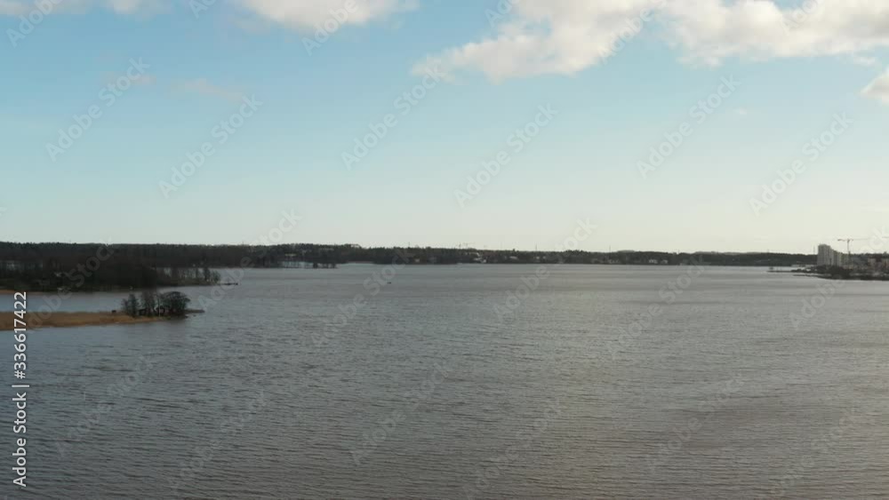 Aerial shot of a beautiful calm nordic lake in Finland with dark waters, pine forest background with sunlight