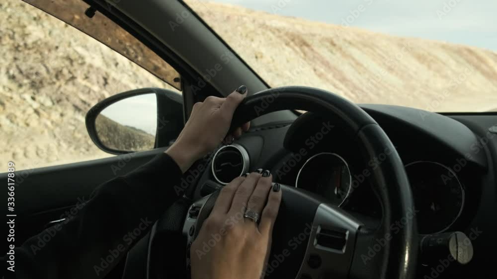View from car on an empty picturesque mountain road in Mongolia on highway, women's hands are on steering wheel, nails are covered with black varnish View from car on an empty picturesque mountain road in Mongolia on highway, women's hands are on steering wheel, nails are covered with black varnish