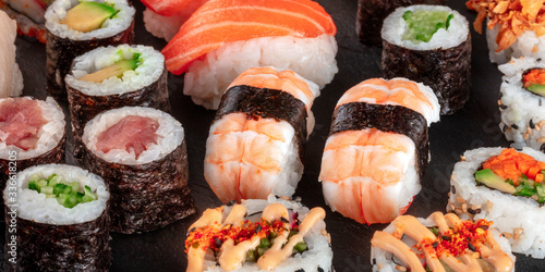 Large sushi set panorama, close-up on a black background. An assortment of various maki, nigiri and rolls