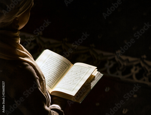Muslim woman under the sunlight reading Quran photo