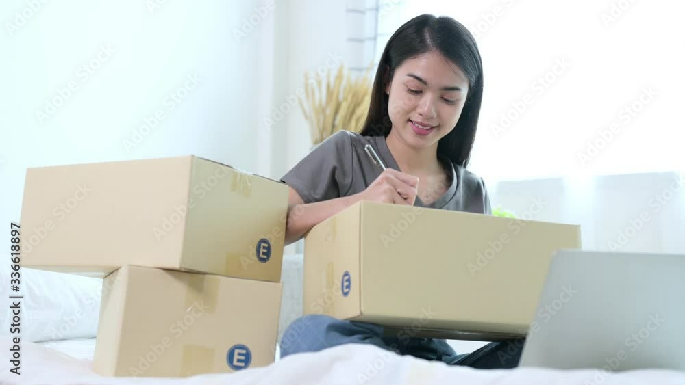 Asian woman merchant are working with her parcel from her home. She has self quarantine social distancing for prevent coronavirus, covid-19. Busines, work from home and online shopping concept. Asian woman merchant are working with her parcel from her home. She has self quarantine social distancing for prevent coronavirus, covid-19. Busines, work from home and online shopping concept.