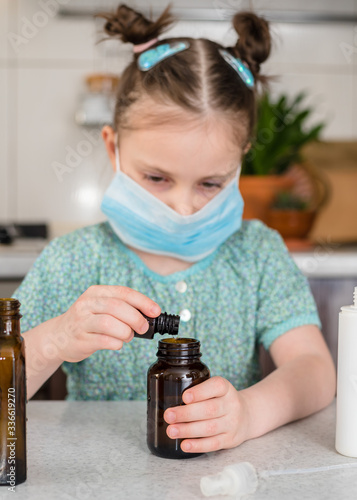 Kid girl makes sanitaizer or antiseptic gel at home. Hygiene during coronavirus epidemic. Concept of safety life. Covid-19 pandemic photo