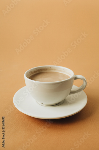 Cup of coffee with milk on ginger background.