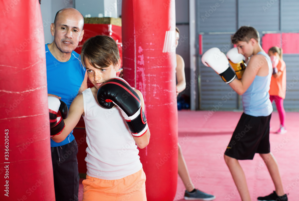 Teenage boy exercising at boxing on punching bag