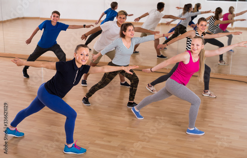 active teenage boys and girls learning in dance hall