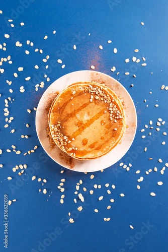 Oat pancakes on a white dish with nuts and syrup, with oatmeal.