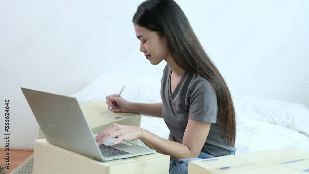 Asian woman merchant are working with her parcel from her home. She has self quarantine social distancing for prevent coronavirus, covid-19. Busines, work from home and online shopping concept. Asian woman merchant are working with her parcel from her home. She has self quarantine social distancing for prevent coronavirus, covid-19. Busines, work from home and online shopping concept.