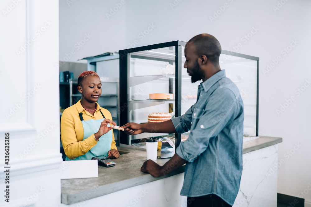 Calm ethnic employee taking client electronic card for order payment in cafe Calm ethnic employee taking client electronic card for order payment in cafe