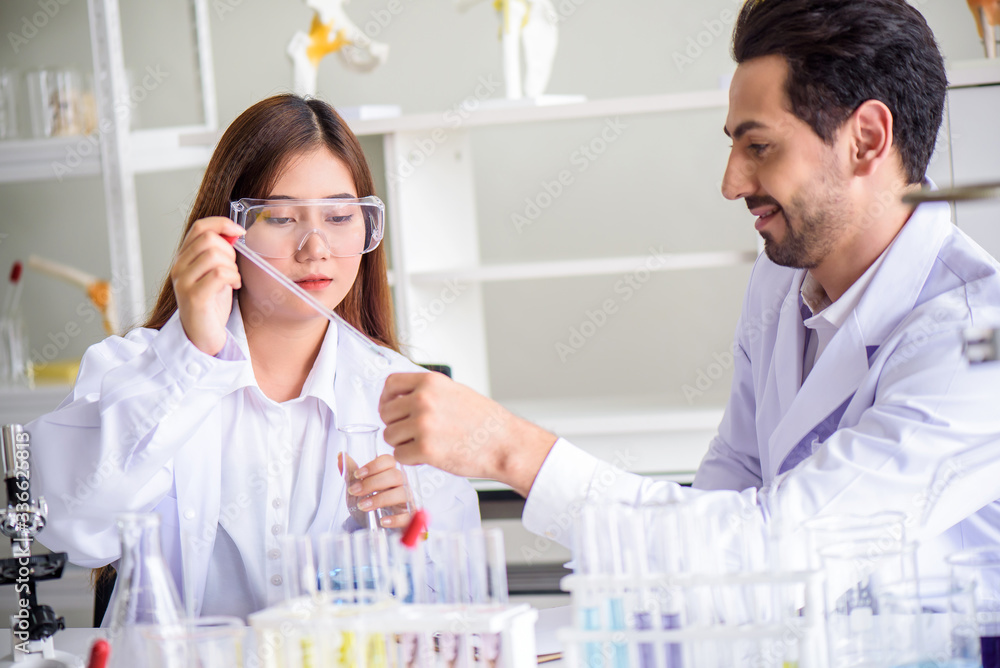 Attractive happiness scientist lab technician assistant analyzing sample in test tube at laboratory. Medical, pharmaceutical and scientific research and development concept. Attractive happiness scientist lab technician assistant analyzing sample in test tube at laboratory. Medical, pharmaceutical and scientific research and development concept.