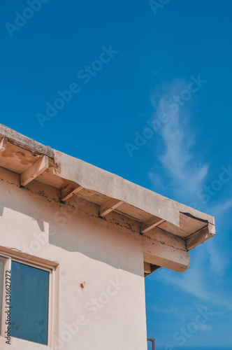 Picture of a roof of an old house building with a window under the bright blue sky. Unique architecture of a flat house rooftop located in the Arabian peninsula in the Middle East. 