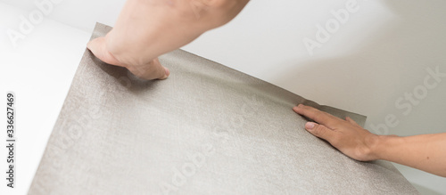 Handyman putting up wallpaper on the white walls at home or house. Installation or renovation for home improvement concept.Banner size