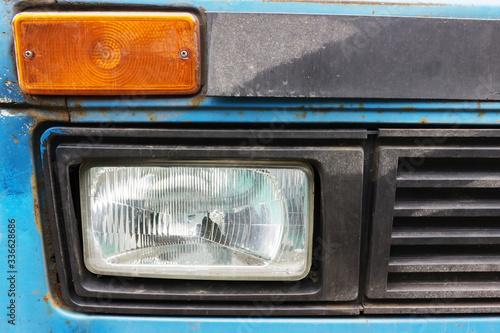side lights of an old car are blue, of unknown make. An old battered car with traces of rust