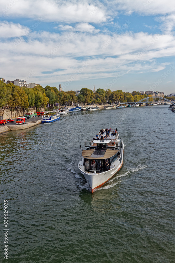 A traditional River Vessel carrying Tourists along a scenic River Cruise through Central Paris on the River Seine.