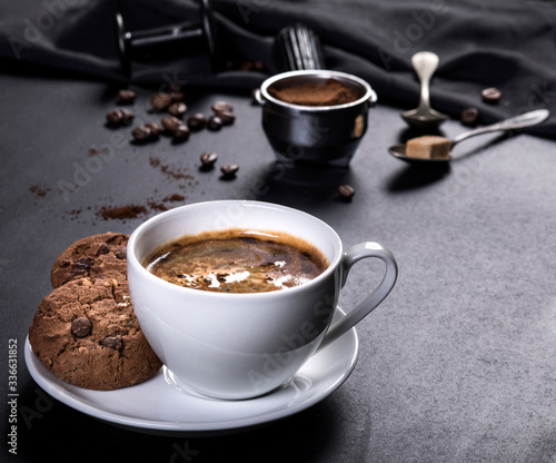 Coffee cup, cookies and utensils for coffee maker on black background