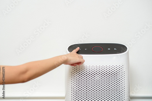 woman is turning on air purifier in home
