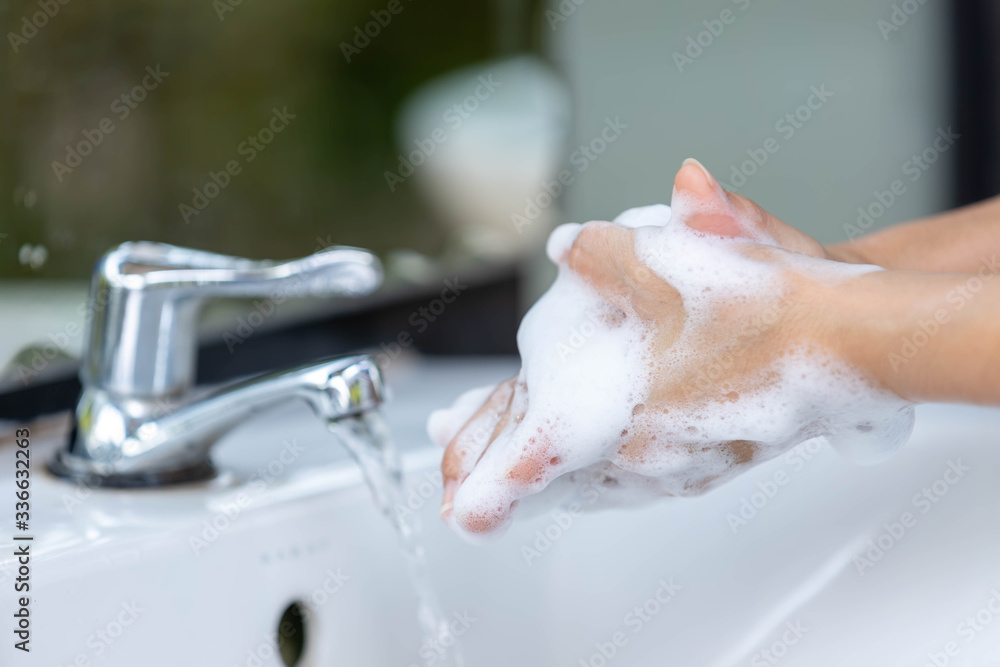 Fototapeta premium Close up woman use soap and washing hands under the water tap in the bathroom for coronavirus and bacteria germs spreading protection,
