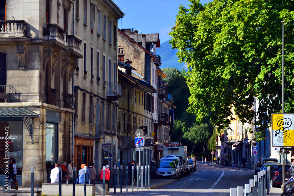 Chambéry, France - August 11th 2017 : View of a busy street with beautiful old buildings. At the end of the road, you can see mountains.