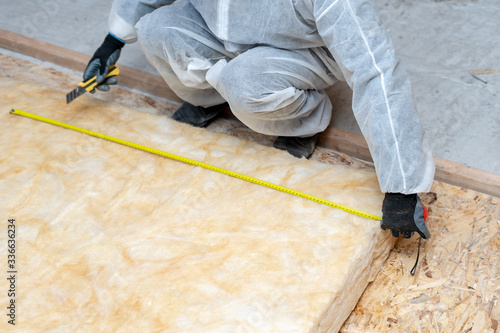 Workman in overalls working with rockwool insulation material photo