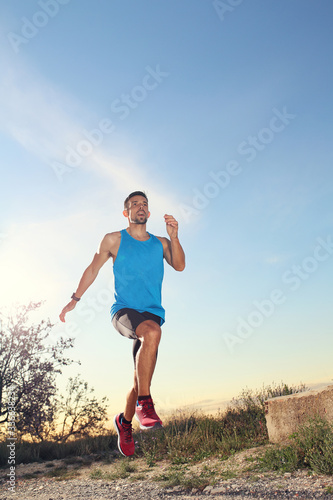 Outdoor training. A man in sports outfit runs along the mountain trail.