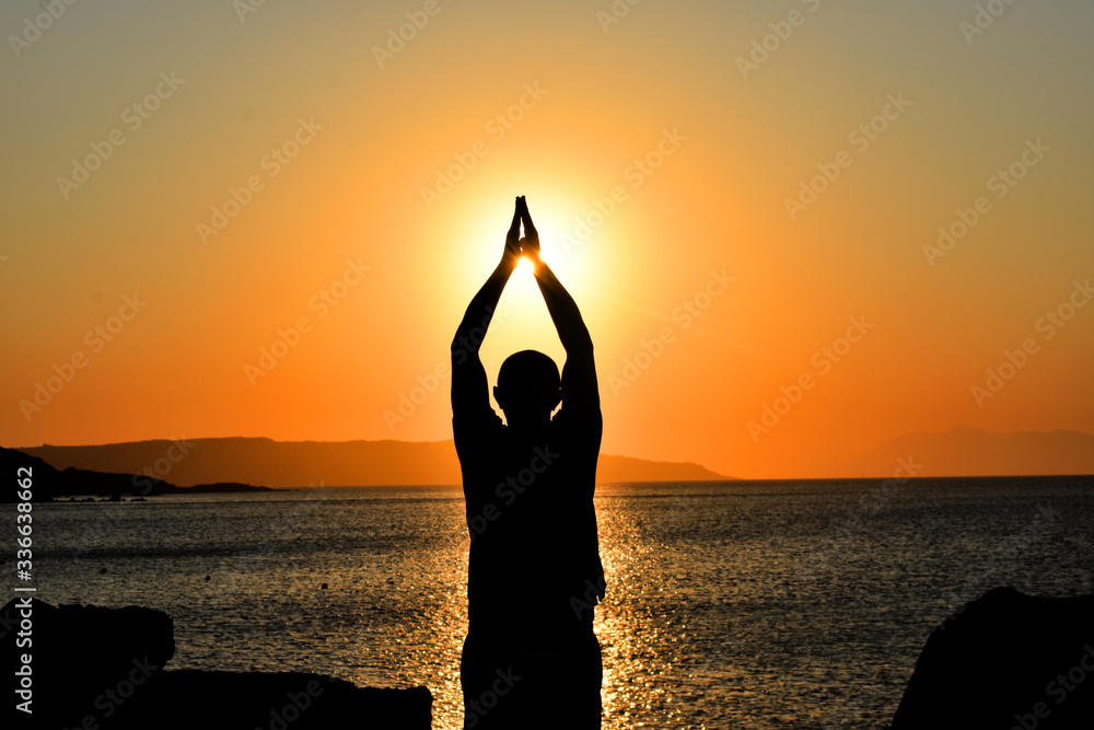 A man meditating in front of the rising sun on the island of Kos in Greece.
