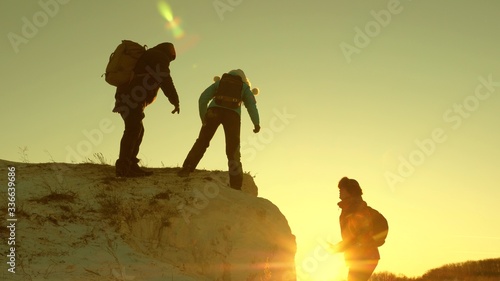 alpinists teamwork. Travel and adventure in mountains at sunset. team of climbers climbs a mountain holding out helping hand to each other. Free woman traveler climb mountain.