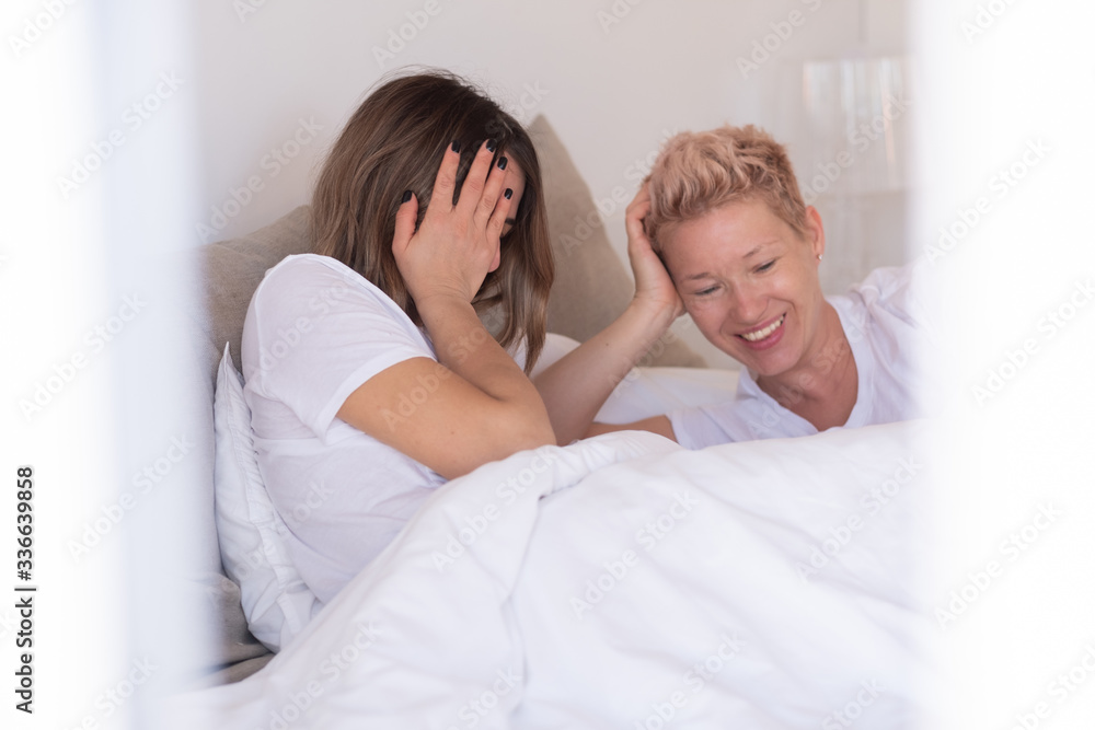 Two women in love laughing on a sunny morning in their cozy bed Two women in love laughing on a sunny morning in their cozy bed