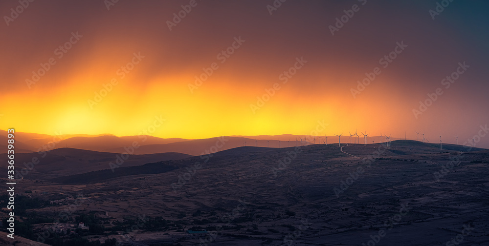 Panorama of windmills  at the the top of a mountain in a stunning sunset