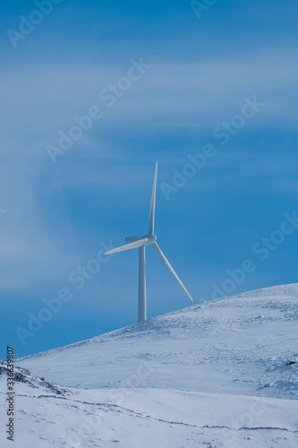 Windmills in asnowed mountain with blue sky
