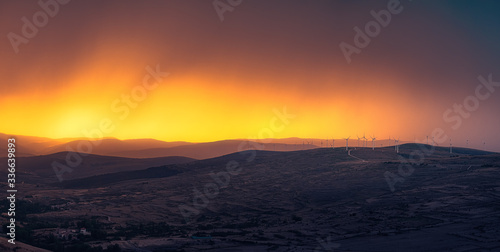 Panorama of windmills at the the top of a mountain in a stunning sunset