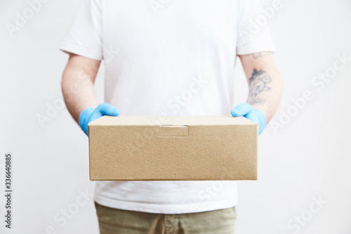 Delivery young  man in  gloves delivering parcel to a young woman during a quarantine. Concept of delivery of goods during the epidemic 