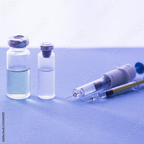 The covid-19 pandemic is concept. Vials of medication and syringe on a blue glass table with window background