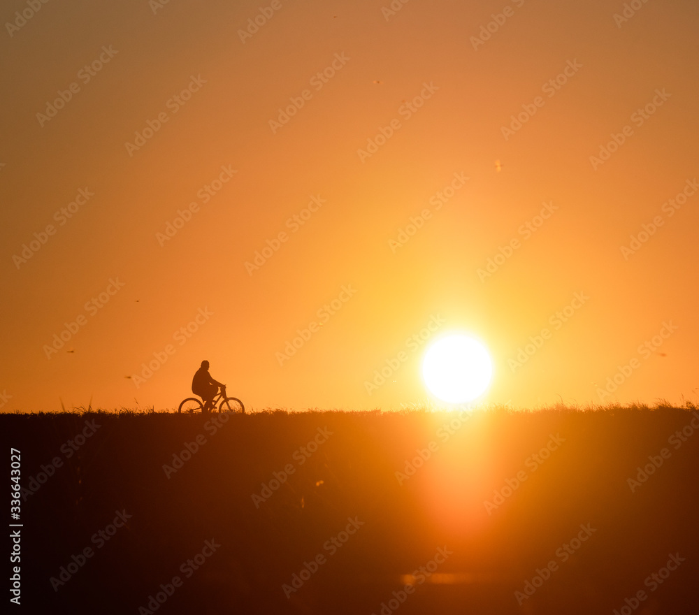 Biker silhouette as the sun sets along the ridge. Biker silhouette as the sun sets along the ridge.