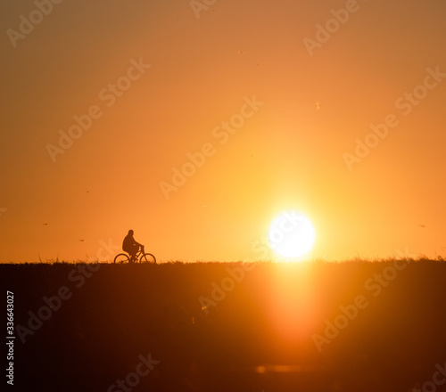 Biker silhouette as the sun sets along the ridge. 