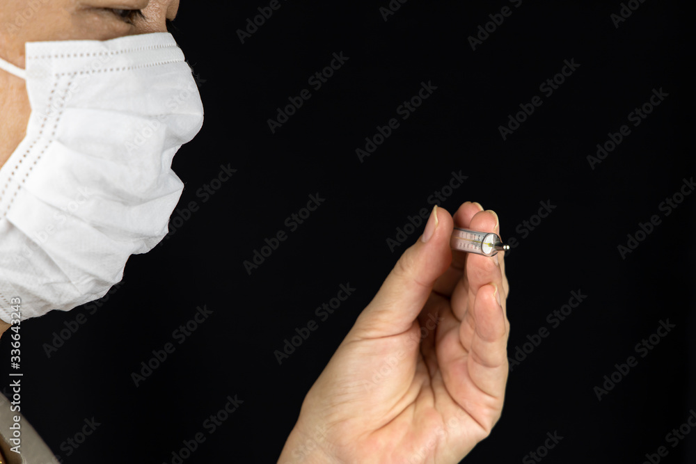 Fototapeta premium Female ware surgical mask and looking at thermometer check their body temperature.