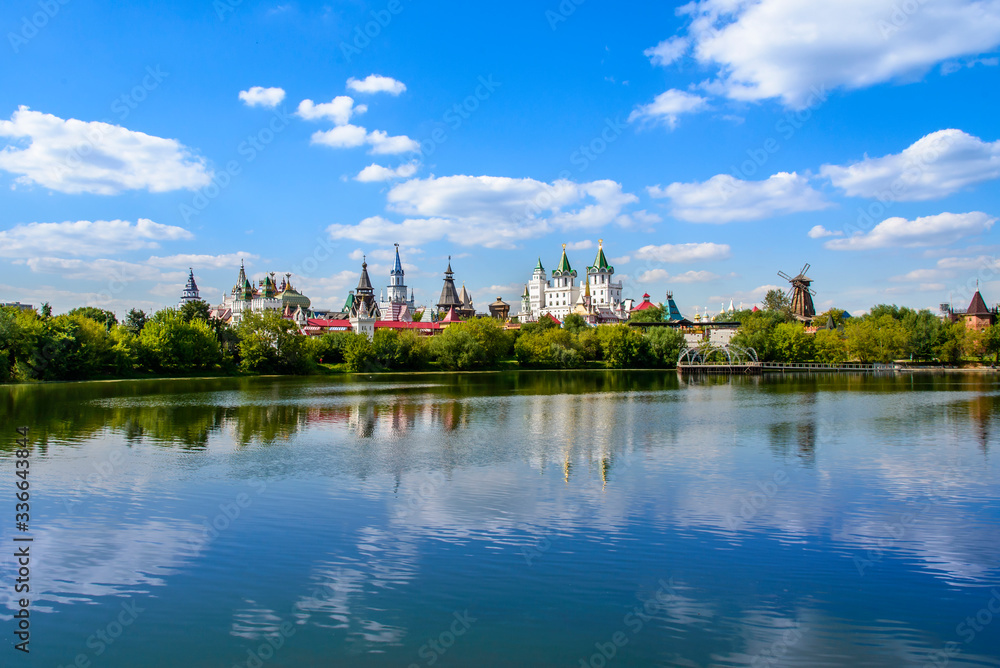 Buildings with towers are reflected on the surface of the pond